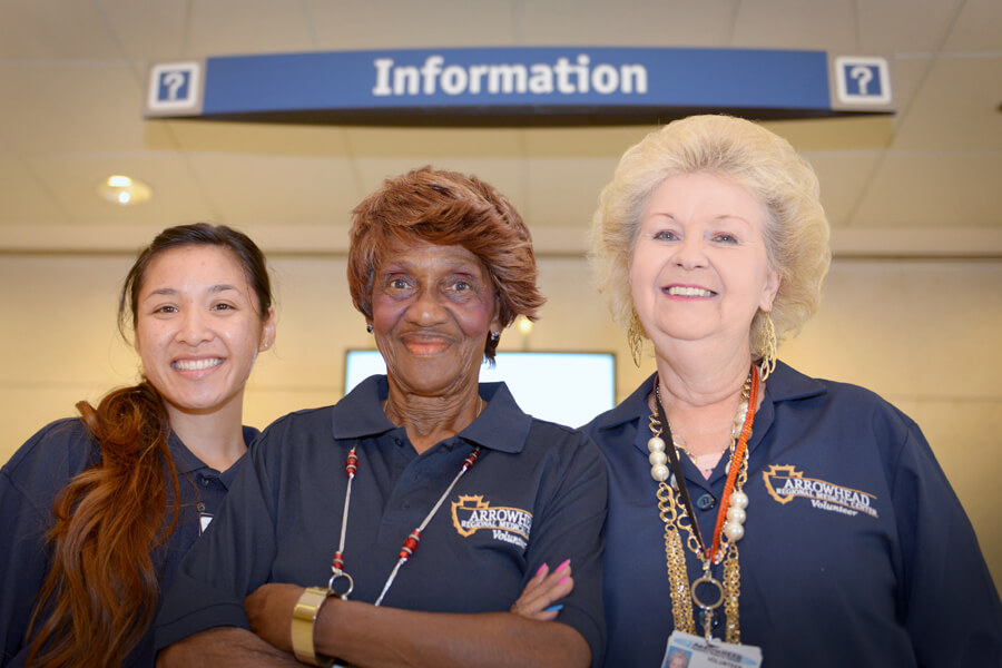 3 ladies in volunteer shirts under information sign